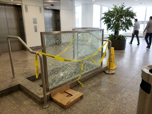 Cracked elevator lobby glass guard taped off in a Toronto office building