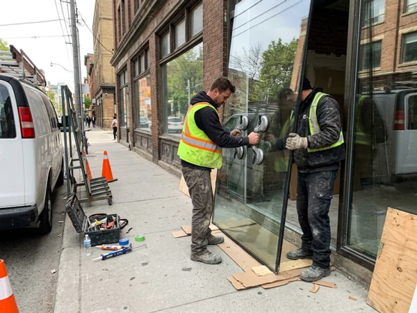 Crew setting a tempered storefront panel on King West